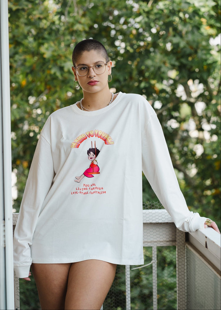 Person wearing a white sweatshirt with a graphic design outdoors