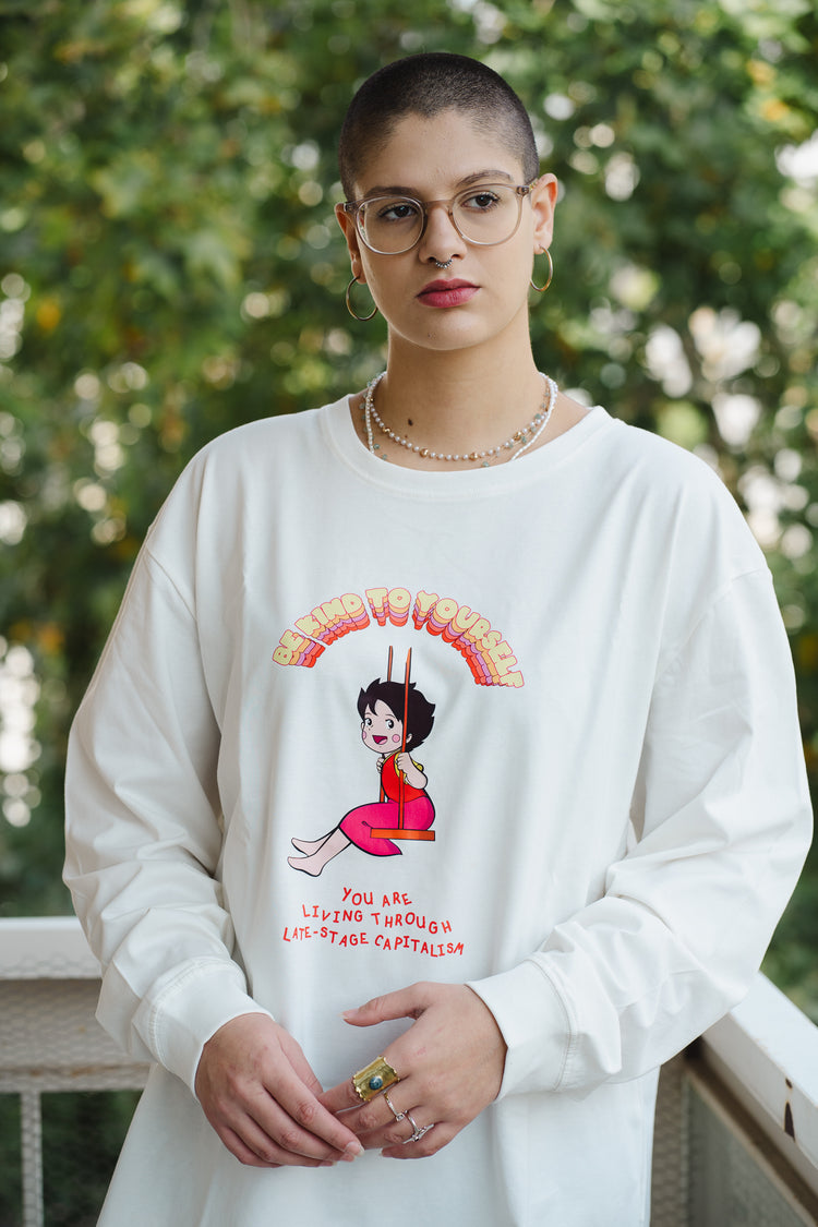 Person wearing a white sweatshirt with a graphic design outdoors