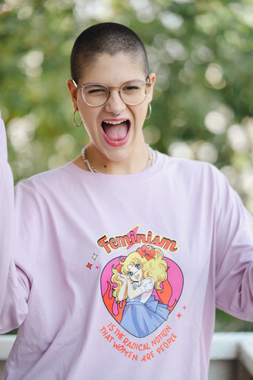 Person wearing a pink t-shirt with a graphic design and text, outdoors.