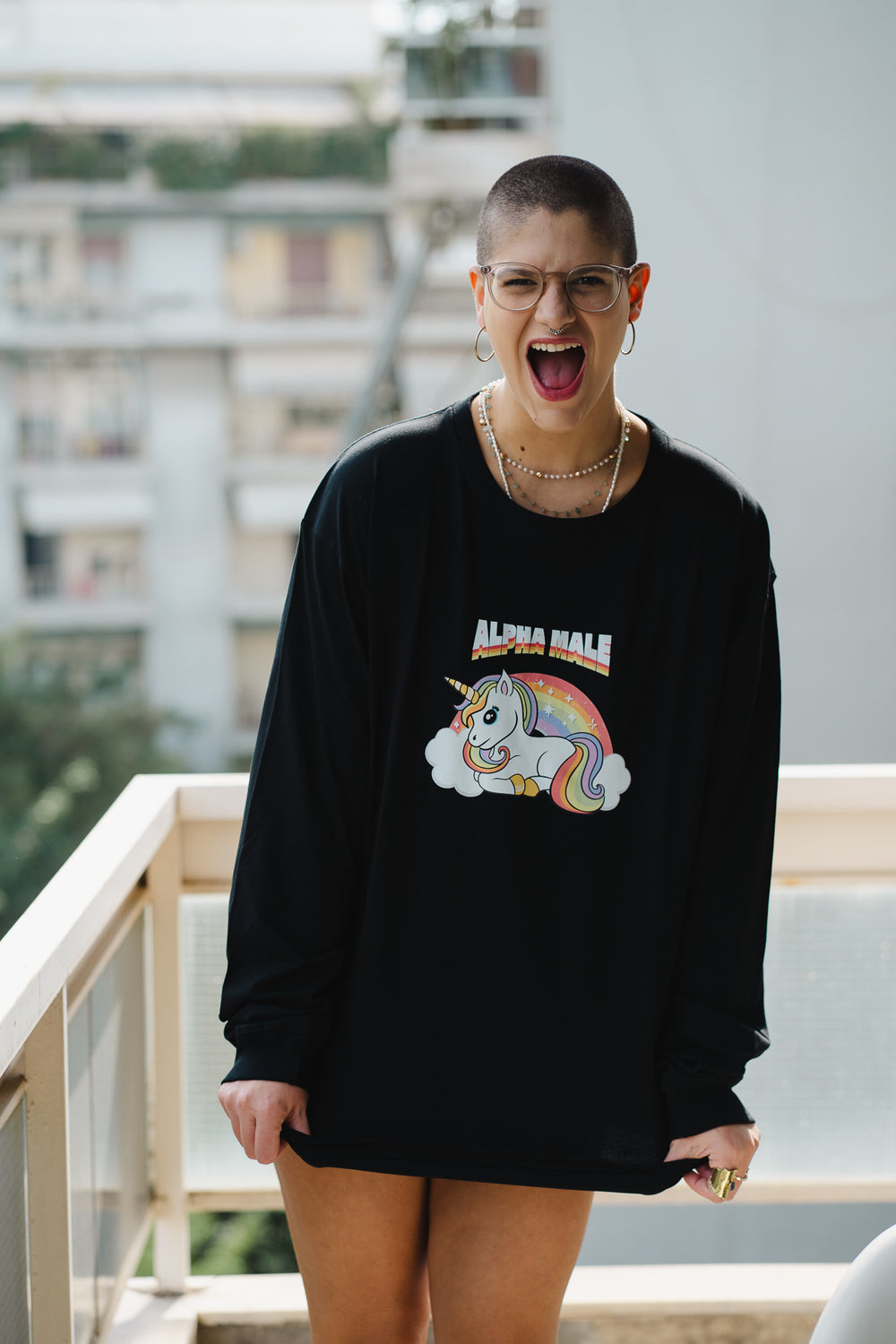 Person wearing a black sweatshirt with a colorful unicorn graphic and text, standing outdoors.