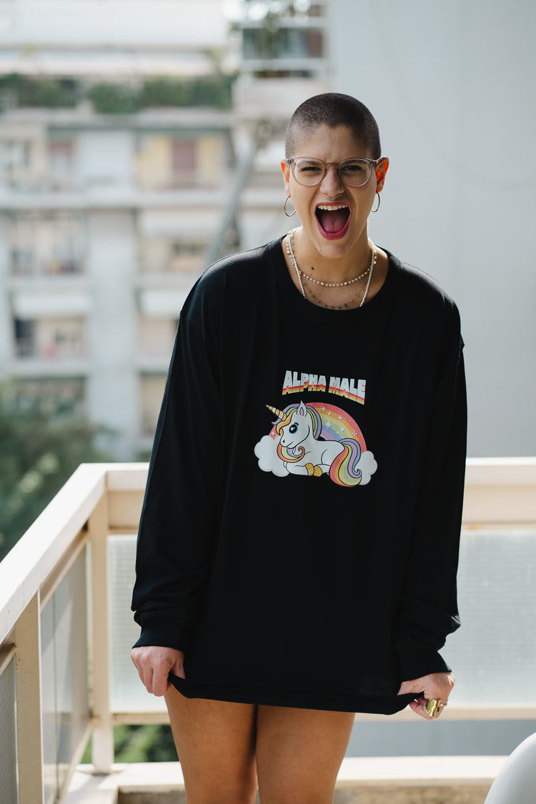 Person wearing a black sweatshirt with a colorful unicorn graphic and text, standing outdoors.