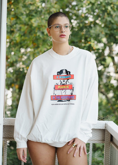 Person wearing a white sweatshirt with a graphic design outdoors