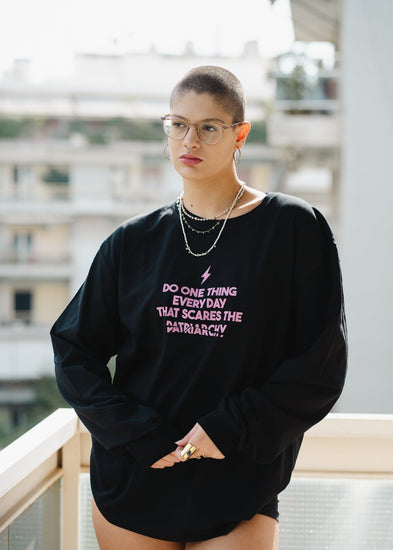 Person wearing a black sweatshirt with a motivational quote, standing on a balcony.
