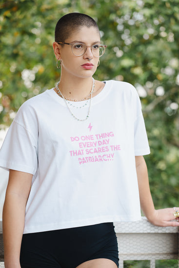 Person wearing a white t-shirt with pink text outdoors
