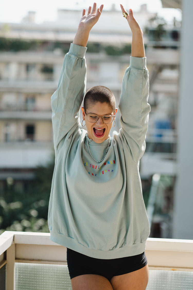 Person wearing a light blue sweatshirt with colorful polka dots on a balcony