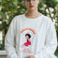 Person wearing a white sweatshirt with a graphic design outdoors
