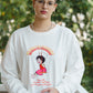 Person wearing a white sweatshirt with a graphic design outdoors