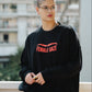 Person wearing a black sweatshirt with 'FEMALE GAZE' text, standing outdoors.