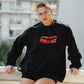 Person wearing a black sweatshirt with 'FEMALE GAZE' text, sitting on a ledge.