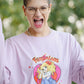 Person wearing a pink t-shirt with a graphic design and text, outdoors.