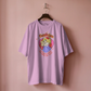 Pink t-shirt with graphic design on a hanger against a pink background