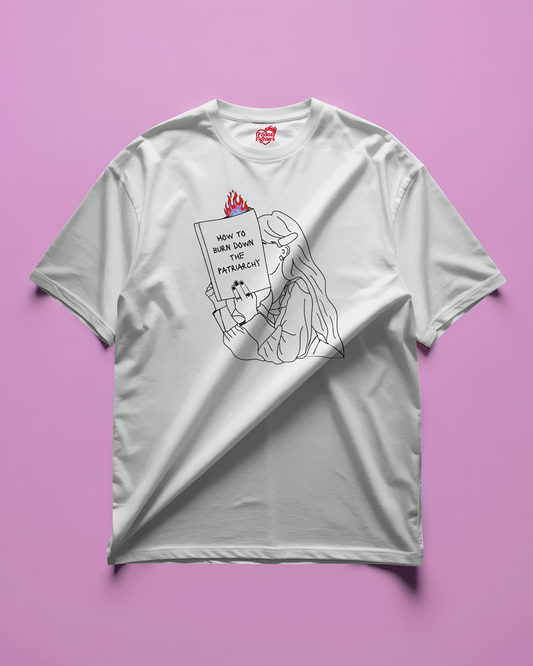 white t-shirt with graphic design of a person holding a book titled 'How to Burn Down the Patriarchy'