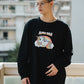 Person wearing a black sweatshirt with a unicorn graphic and text, standing outdoors.