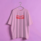 Pink t-shirt with 'FEMALE GAZE' text on a hanger against a purple background