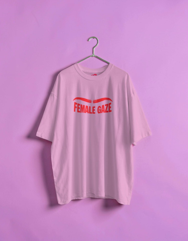 Pink t-shirt with 'FEMALE GAZE' text on a hanger against a purple background