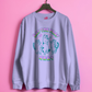 lilac sweatshirt with graphic design and text on a pink background