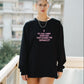 Person wearing a black sweatshirt with text on it, standing on a balcony.