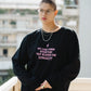 Person wearing a black sweatshirt with a motivational quote, standing on a balcony.