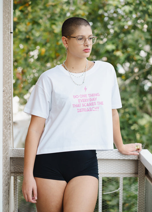 Person wearing a white t-shirt with text and black shorts on a balcony