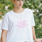 Person wearing a white t-shirt with pink text outdoors