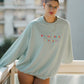 Person wearing a light blue sweatshirt with colorful text on a balcony