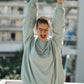 Person wearing a light blue sweatshirt with colorful polka dots on a balcony