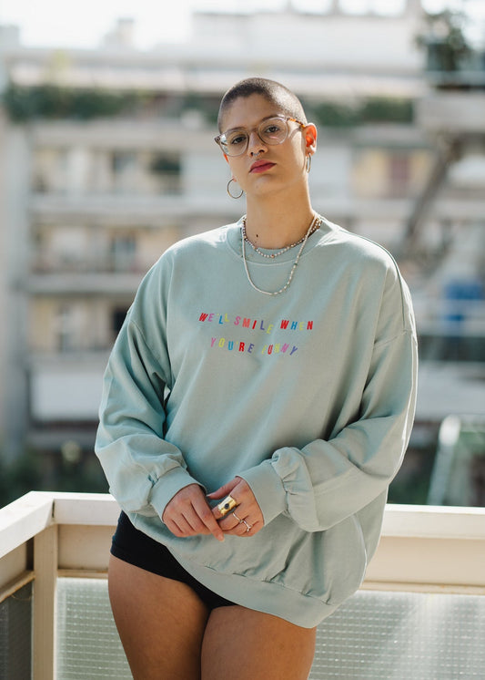 Person wearing a light blue sweatshirt with colorful text, standing on a rooftop.