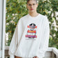 Person wearing a white sweatshirt with graphic design outdoors