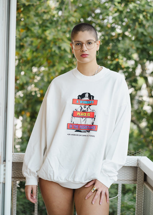 Person wearing a white sweatshirt with graphic design outdoors